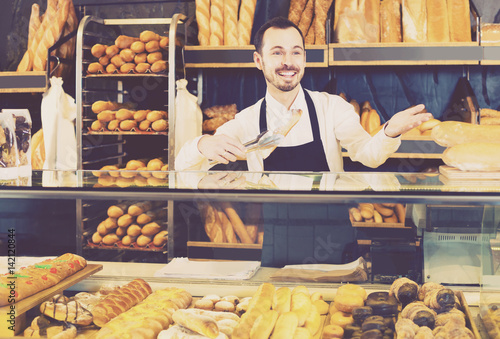 "Male shop assistant demonstrating fresh delicious pastry ...