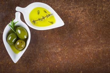 Aceite de oliva virgen extra y aceitunas con hierbas y especias sobre una superficie vintage con espacio para texto