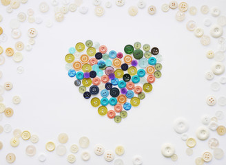 Colorful heart made of buttons. Background of multi-colored buttons. Abstract background. Pattern of buttons on a white background.