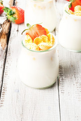 Summer light breakfast: homemade organic yogurt with cornflakes and fresh strawberries. On a white rustic wooden table copy space