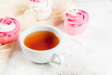 The concept of celebrating the mother's day. Spring relax. Cakes in the form of flowers (roses), with a cup of freshly brewed black tea, on a white stone table. Copy space