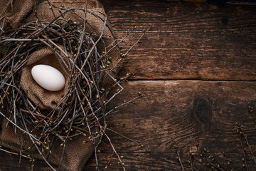 One big egg in the nest with spring branches, on an old wooden table