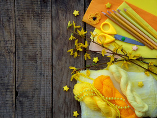 Composition of yellow accessories for hobby on grey wooden background. Knitting, needlework, sewing, painting, origami. Small business. Income from hobby.