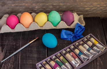 Colorful easter egg with painting brush on wooden table . Happy Easter