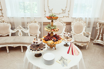 The white restaurant room in vintage style. fruit and pastries on white vintage stands