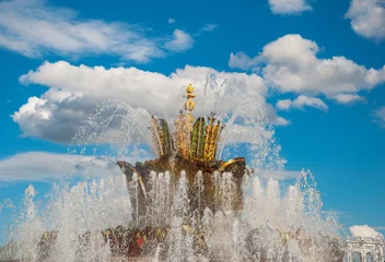 Photo sur Plexiglas Fontaine Jets and splashes of the fountain against the blue sky and white clouds