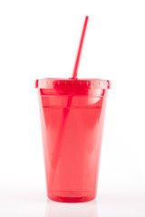 Red plastic travel cup with straw on a white surface. Isolated on white background.