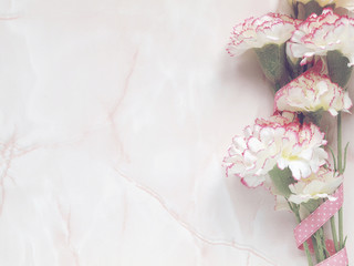 Pink flowers with pink dotted ribbon on marble background. Flat lay. Top view