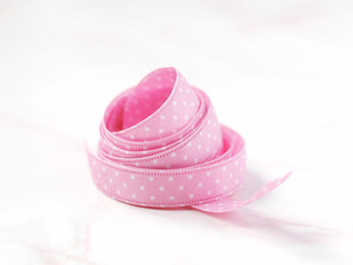 Pink dotted ribbon on light marble background