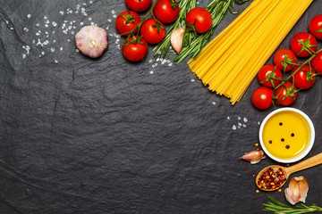 Pasta ingredients. Spaghetti with ingredients sweet basil, tomato, garlic and parmesan cheese on dark background. Top view