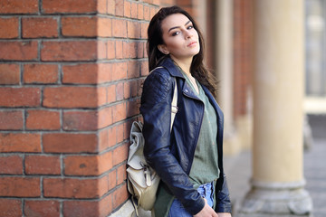 Young woman sitting against the wall. On the streets of town