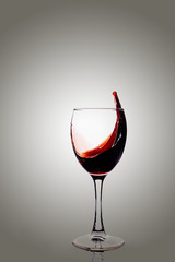 Red wine on wineglass with splash.