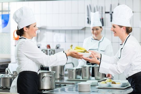 K&uuml;chenbrigade in einer Catering-K&uuml;che richtet Speisen an