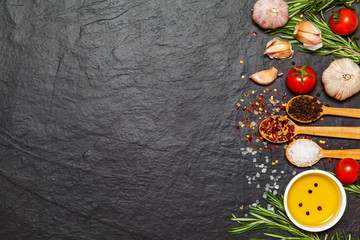 Colorful spices in spoons and tomatoes on dark vintage background. Top view. Food and cuisine ingredients.