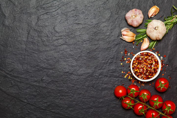Colorful spices in spoons and tomatoes on dark vintage background. Top view. Food and cuisine ingredients.