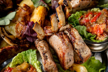 Meat plate with delicious pieces of meat, salad, ribs, grilled vegetables, potatoes and sauce. Close up image with selective focus