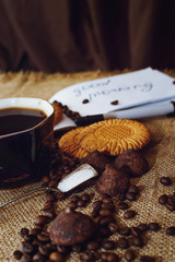 Coffee beans and chocolate candies on sackcloth close up. Coffee and sweets background.