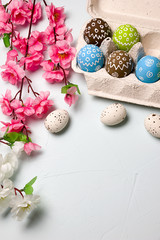 Fototapeta na wymiar Painted easter eggs and branches of spring sakura closeup on a light blue background with space for congratulation
