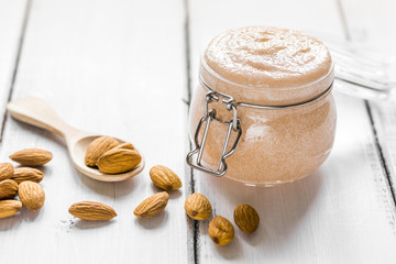cosmetic set with almond scrub on table background