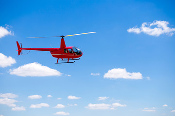 Red helicopter in the blue sky.