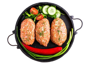 raw cutlets with vegetables, herbs and spices in a frying pan
