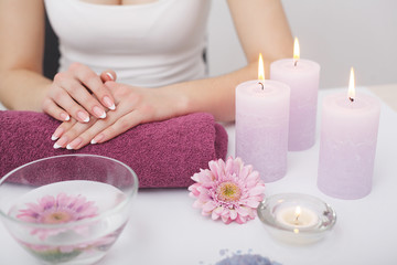 Beautiful manicure with orchid, candle and towel on the white wooden table.