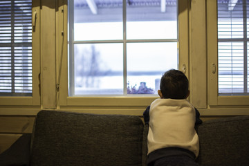 Little boy watching through the window