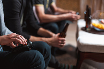 Close up men at home with a beer and chips with joysticks in hand playing computer video game. The concept of friendship, technology and weekend