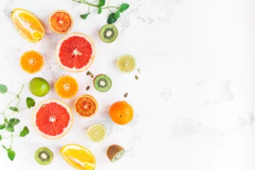 Deurstickers Vruchtenachtergrond. Kleurrijk vers fruit op witte tafel. Sinaasappel, mandarijn, limoen, kiwi, grapefruit. Platliggend, bovenaanzicht, kopieerruimte © Flaffy