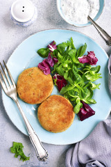 Salmon patties with mix salad leaves and yogurt sauce.Top view.