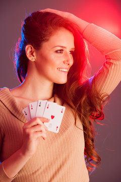Beautiful brunette holding four aces as a sign for poker game, gambling and casino