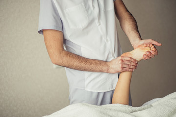 Young, smiling PT exercising her little patient's leg in a very bright rehabilitation office