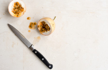 High angle view of panama gold passionfruit in halves with knife on cream limestone background  and...