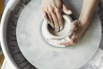 Fototapeta premium Ceramic working process with clay potter's wheel, close-up of woman hands
