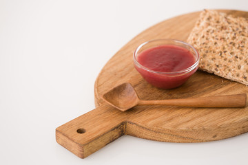 Top view on wooden board with organic wholegrain crisps with strawberry jam on kitchen table. Healthy Breakfast or snack. Healthy food and eating.