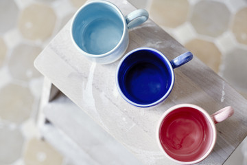 Samples handmade ceramic colored cups on wooden table, working process in studio