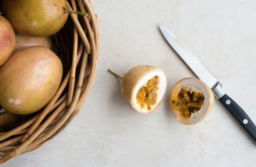 High angle view of panama gold passionfruit in halves with knife and basket of fruit (selective...