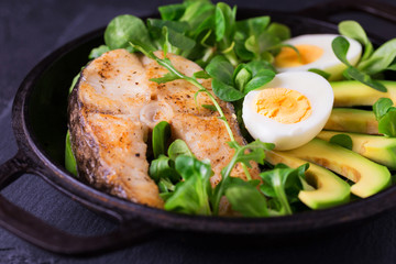 Grilled sheatfish fish steak with avocado, arugula and salad