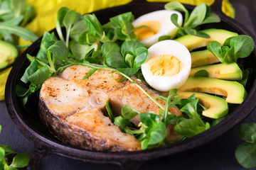 Grilled sheatfish fish steak with avocado, arugula and salad