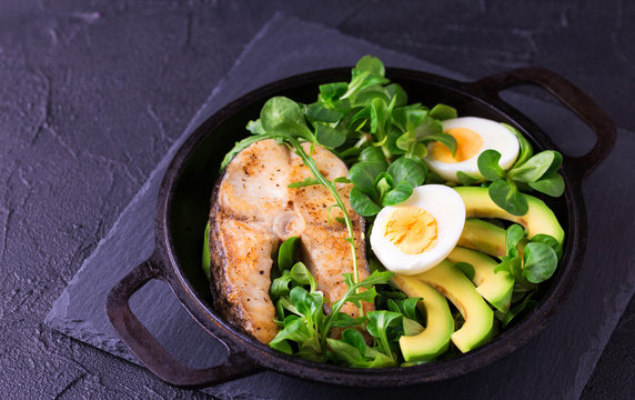 Grilled sheatfish fish steak with avocado, arugula and salad