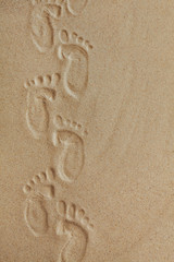 Cute baby footsteps on sandy beach with space for text or desighn