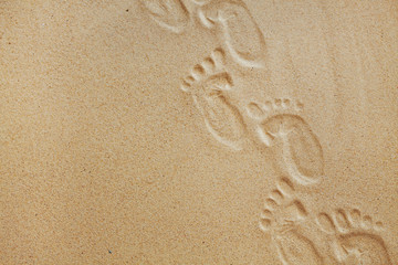 Cute baby footsteps on sandy beach with space for text or desighn
