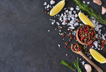 Mix of peppers with salt, rosemary and garlic on shale stone. Black food background with spices....
