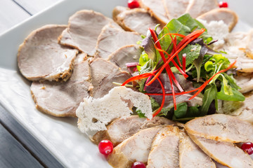 Meat plate with delicious pieces of sliced ham, herbs and meat with cranberry. Close up with selective focus