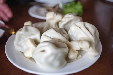 Hinkali in white plate on wooden table