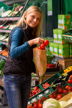 Junge Frau kauft im Biomarkt Tomaten