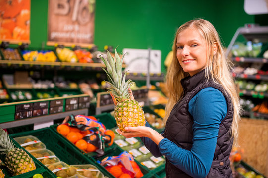 Junge Frau kauft im Supermarkt eine Ananas