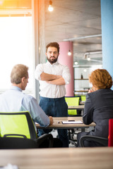 Fototapeta premium Toned of businessman knows how to get positive assessment from his employees. Handsome man posing with folded or crossed hands in office.