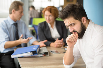 Young applicant having stress before interview while business employees communicating on...