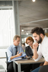 Bearded young student looking sad, because he failed interview in office. Handsome man thinking how to get successful or positive assessment.